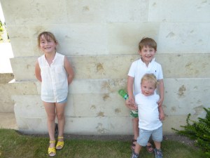 The children are standing next to one of the walls with shell damage incurred during WW2